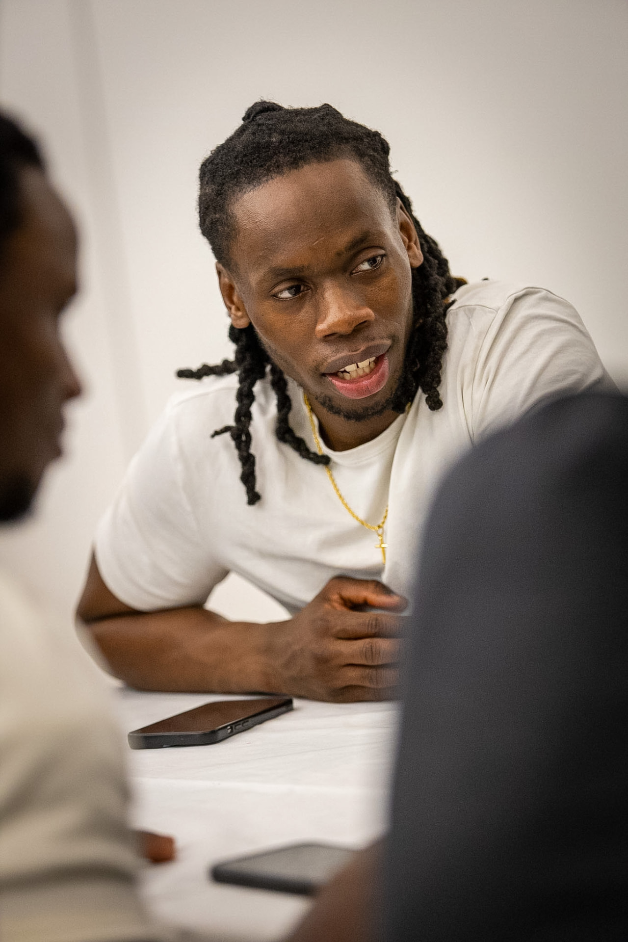A young man talking across a table with other men