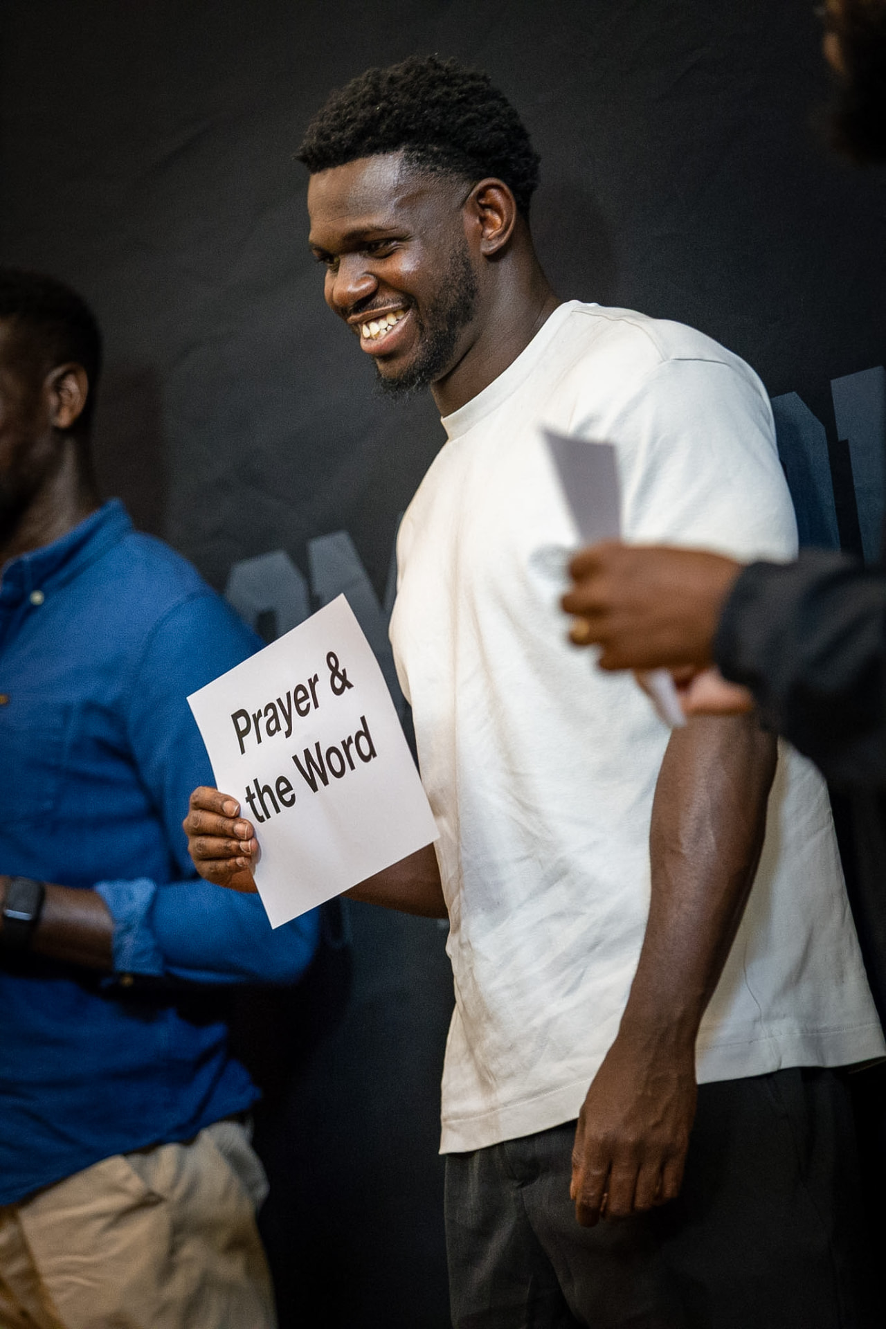 A man holding a card that reads Prayer and the Word