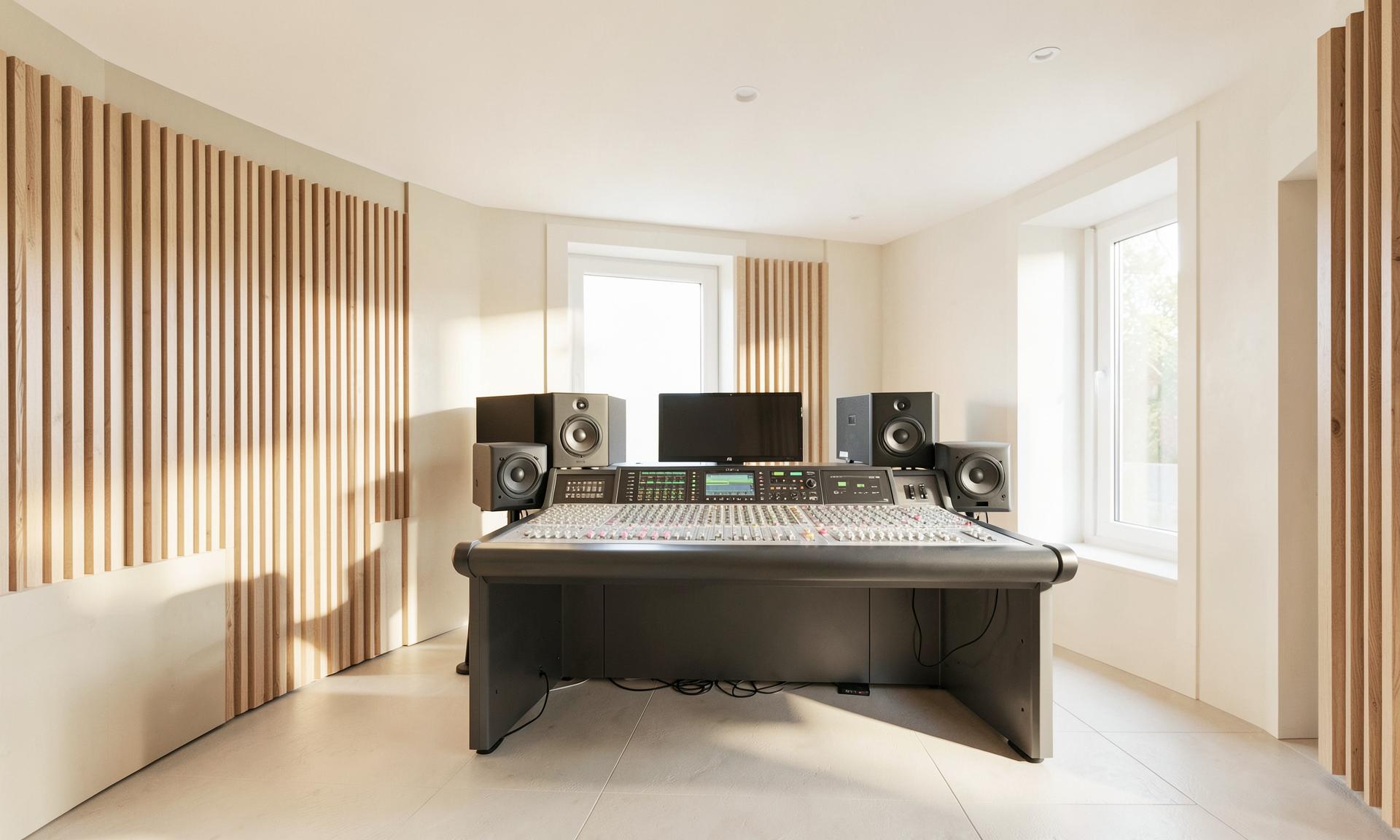 A bright, modern sound studio with a mixing console and wooden acoustic panels